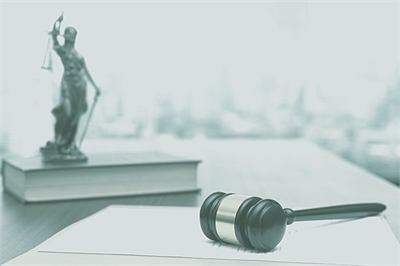 [ai] A wooden gavel lies on a stack of legal documents, with a statue of Lady Justice in the background, symbolizing law and justice in a professional legal setting.
